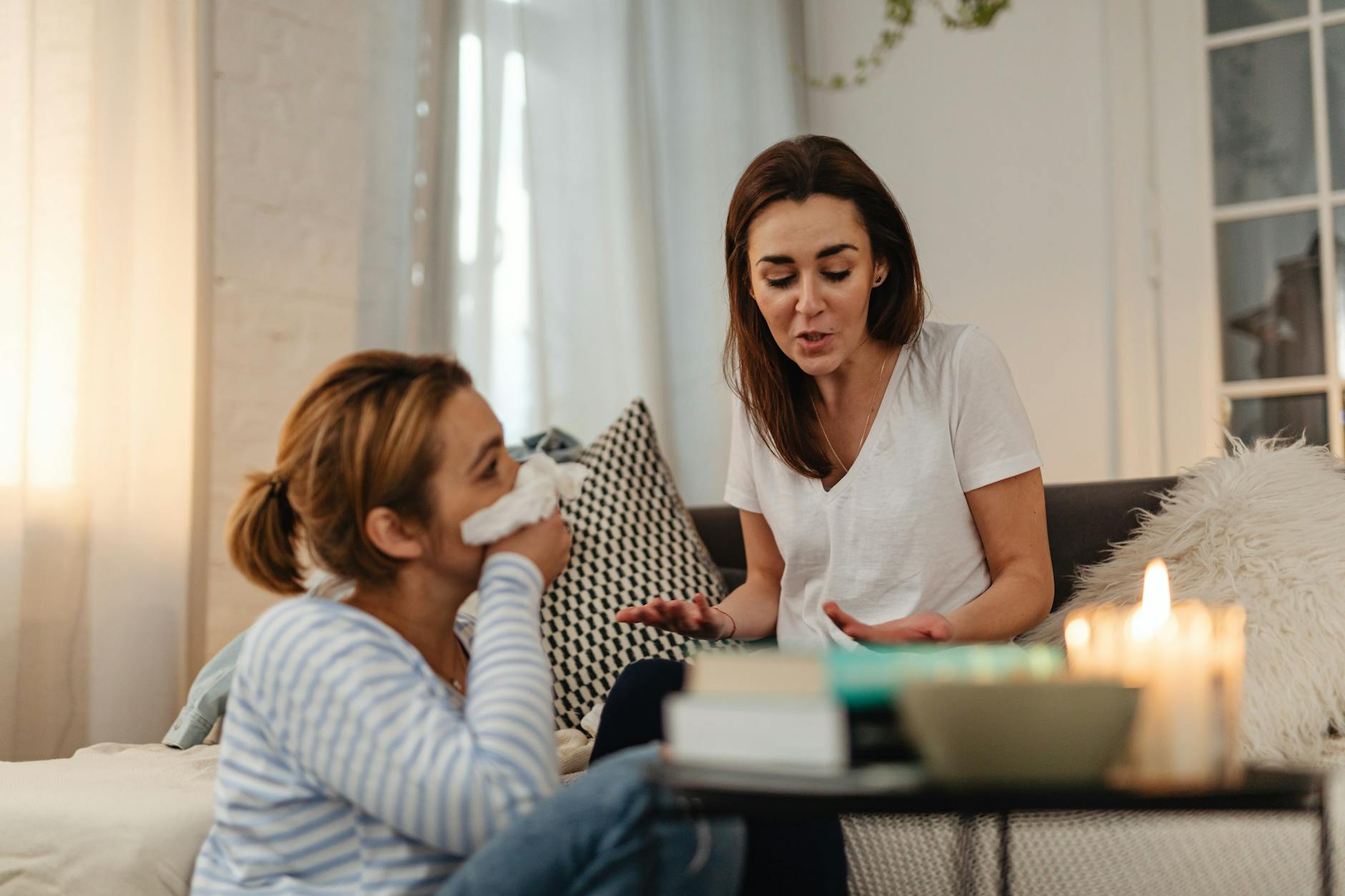 Two people having a warm conversation in a cozy home environment with candles, representing the personal care relationships at Hearthstone
